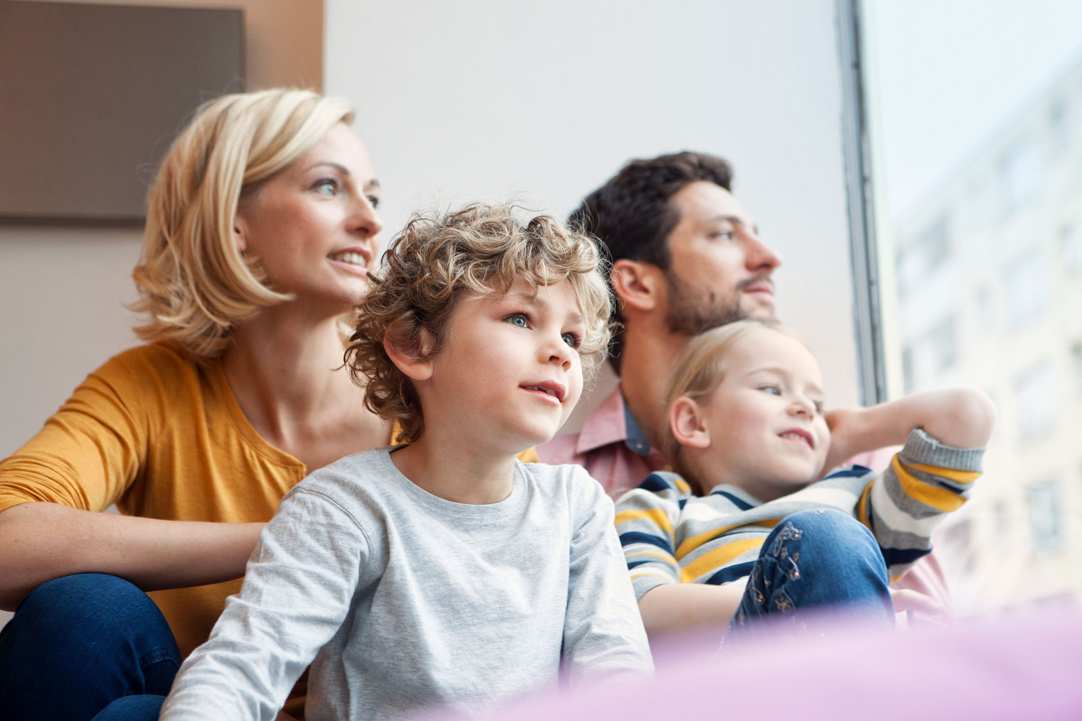 Eltern mit zwei Kindern schauen gemeinsam aus dem Fenster