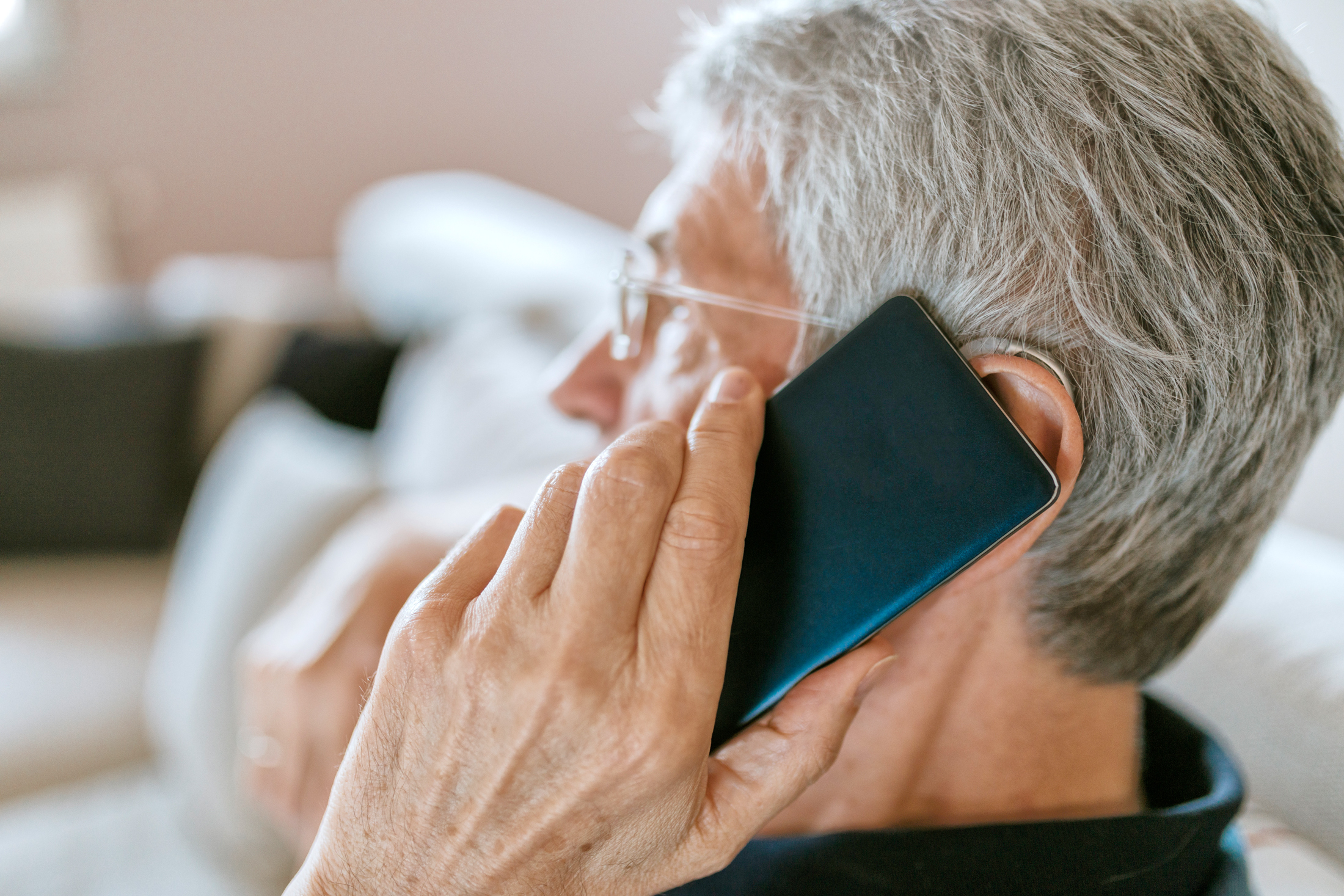 Älterer Herr mit Hörgerät telefoniert mit dem Handy