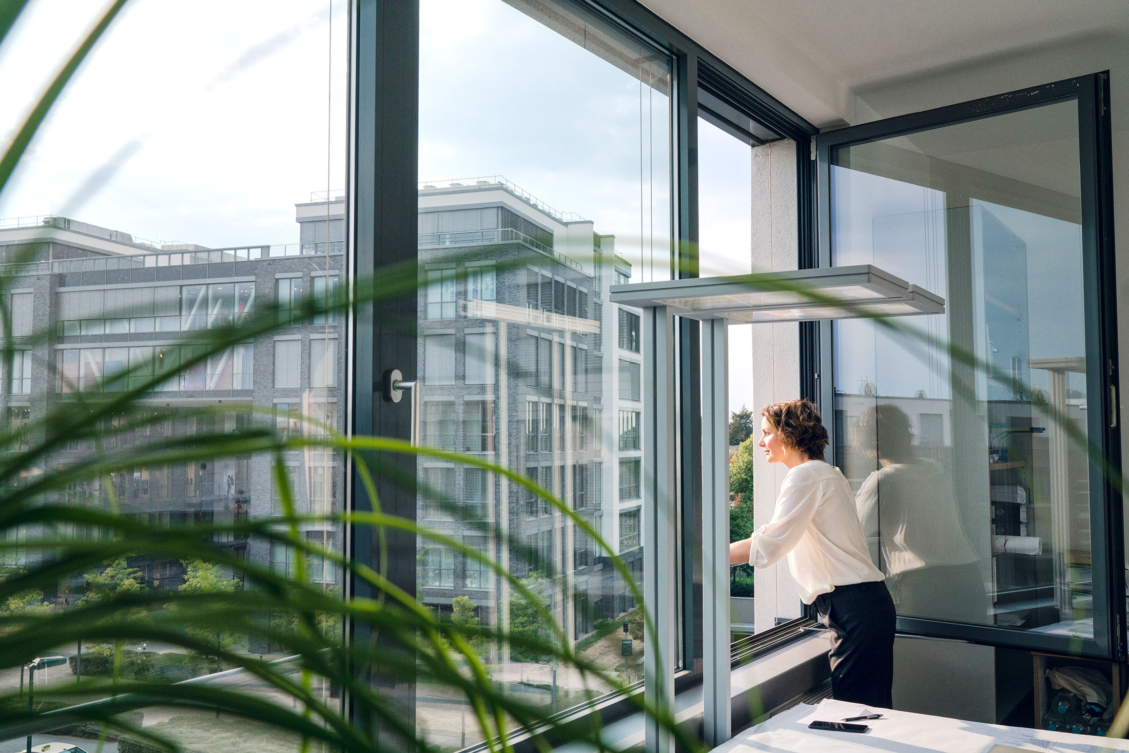 Geschäftsfrau steht in ihrem Büro und schaut aus dem Fenster