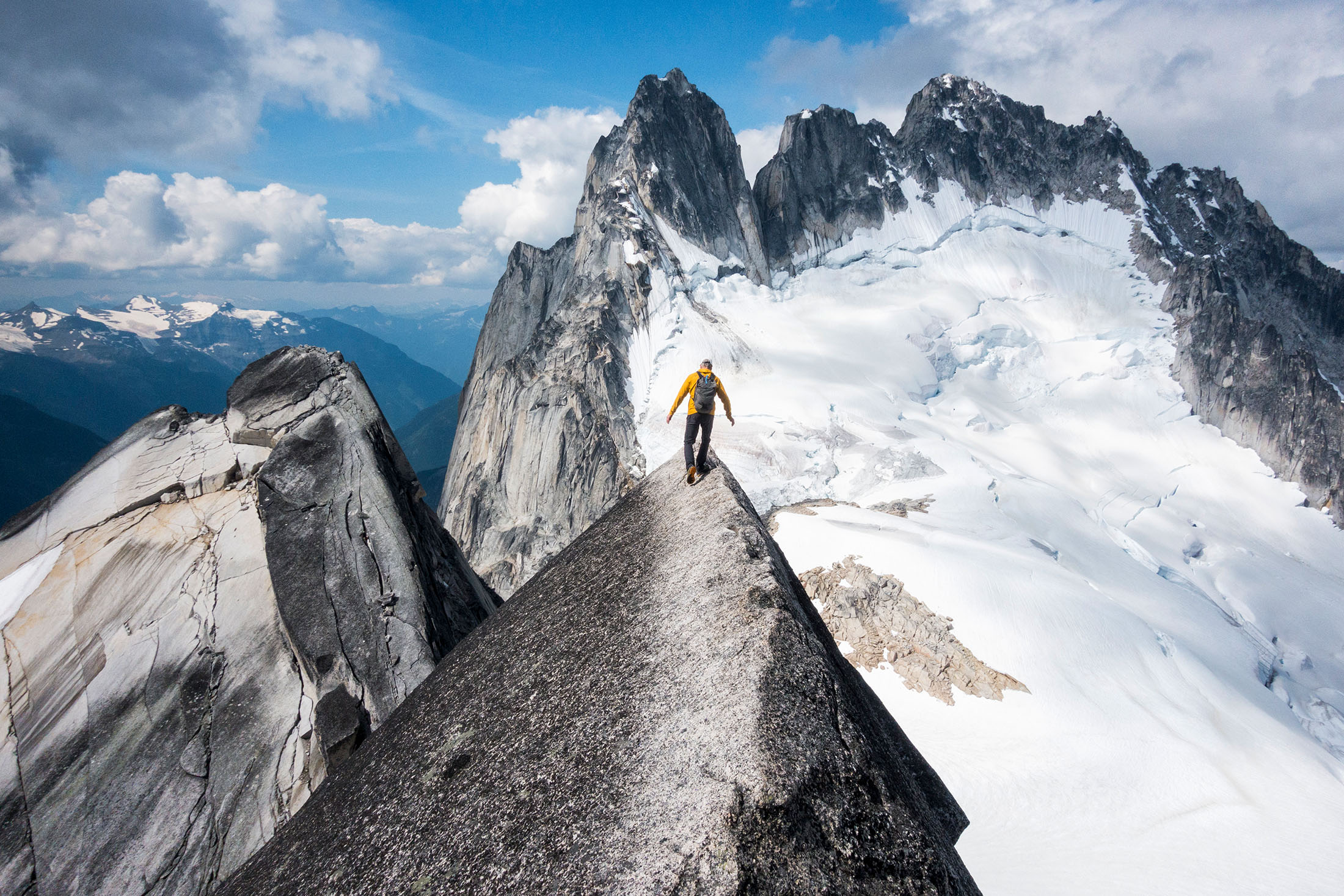 Wanderer wandert auf der Spitze eines Berges der mit Schnee bedeckt ist