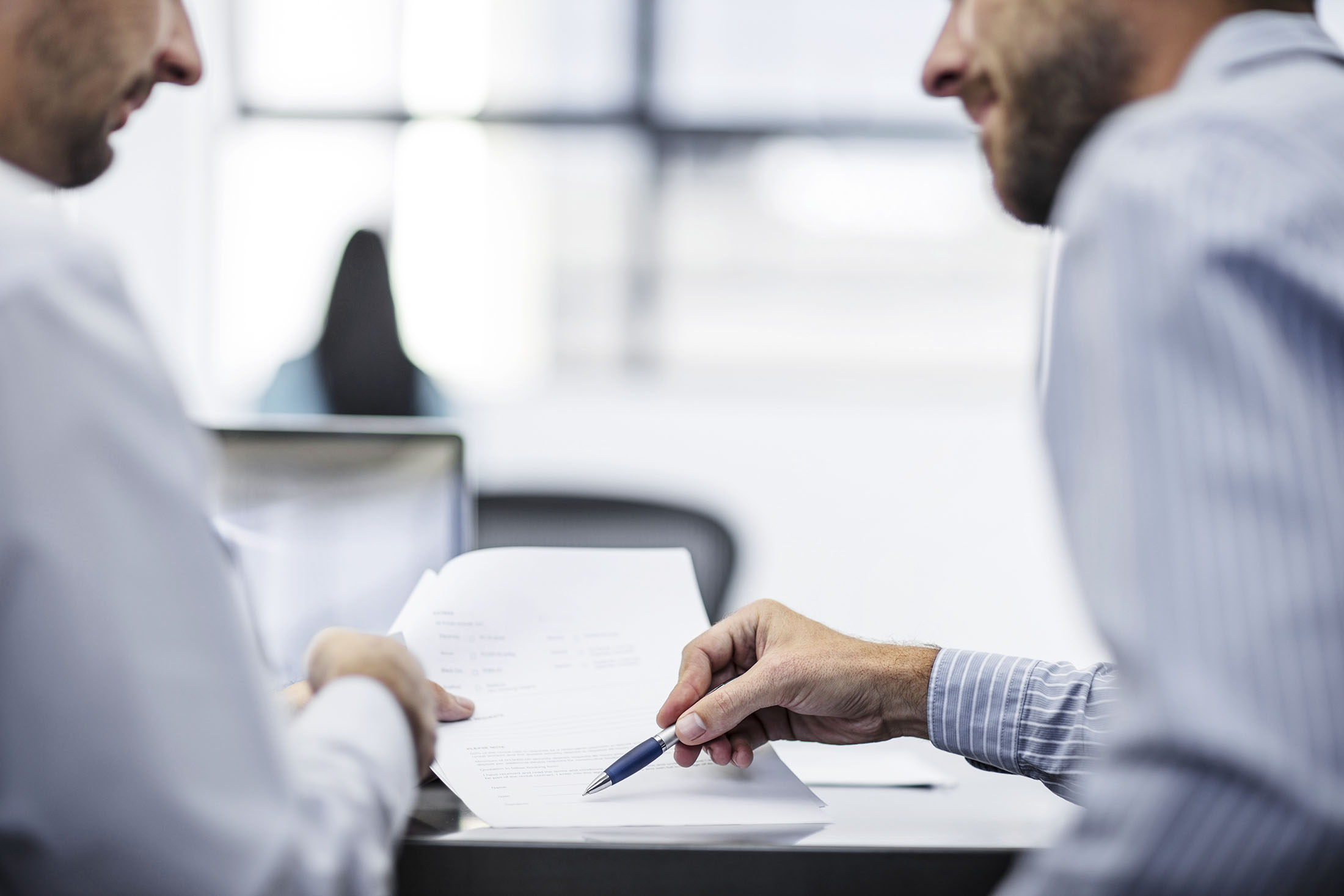 Zwei Männer besprechen Unterlagen und zeigen mit Stift auf Details