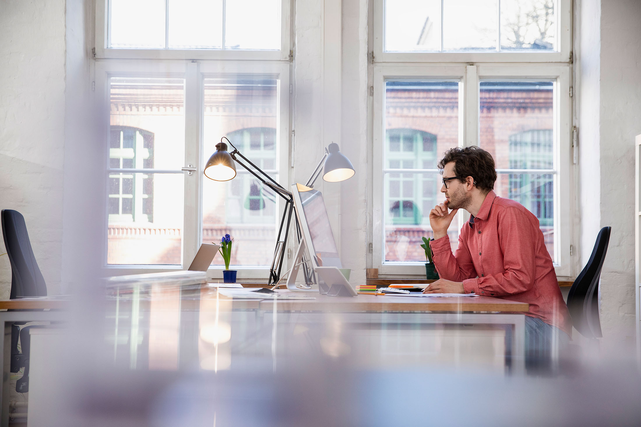 Mann sitzt im Büro am Schreibtisch und schaut auf seinen Computer