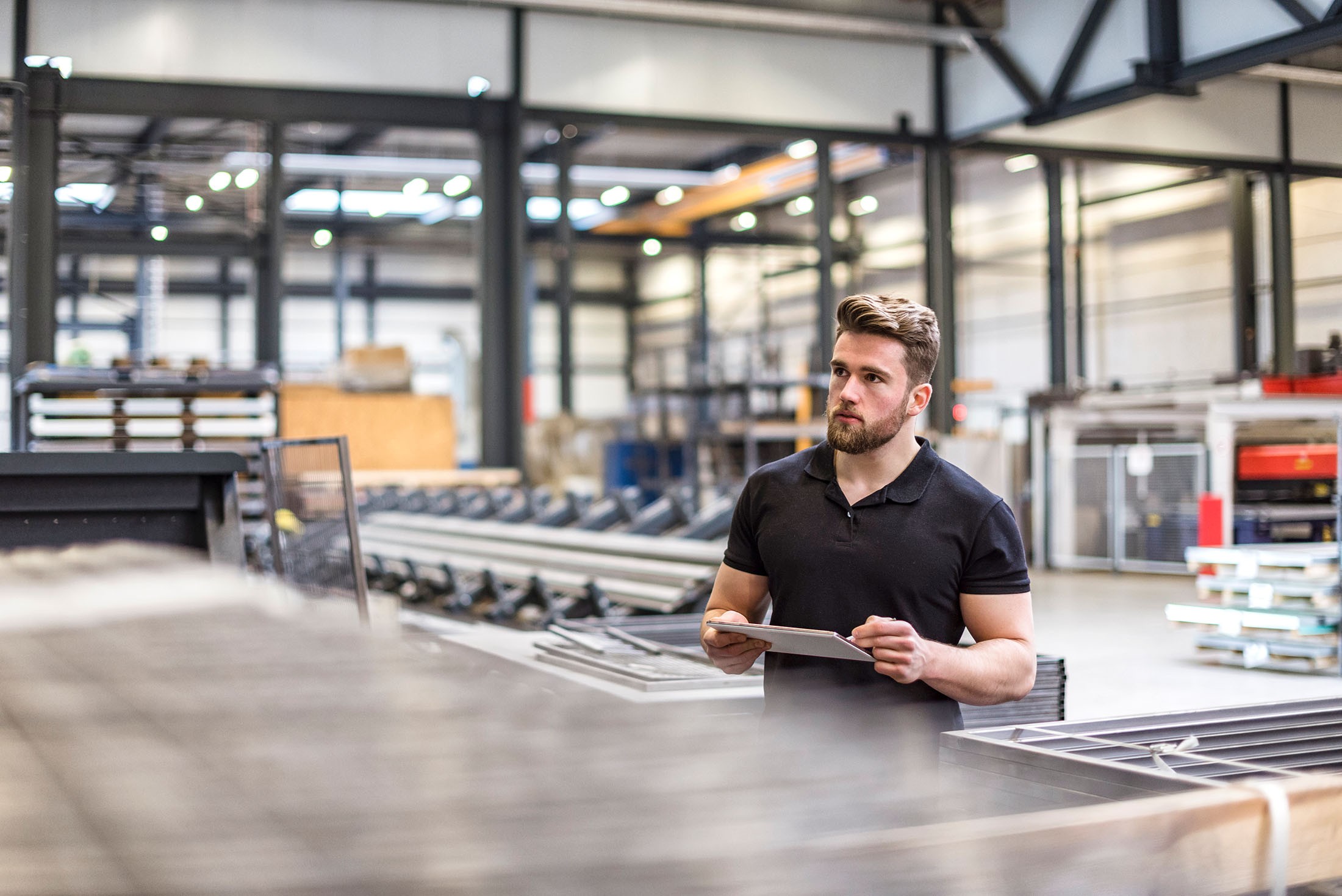 Mann benutzt ein Tablet in der Fabrikhalle