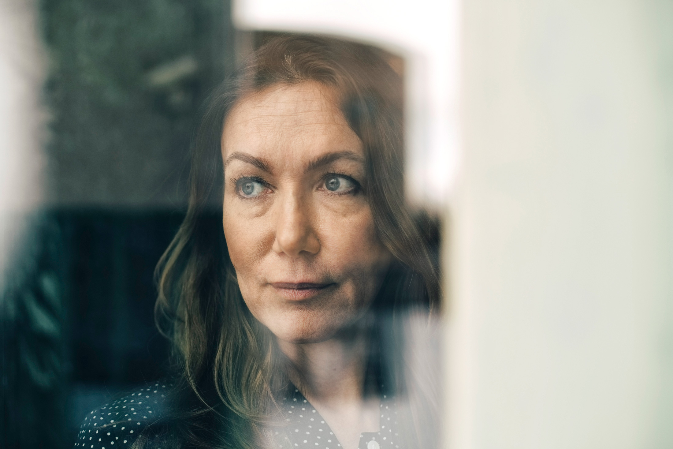 Ältere Frau schaut durch ein Fenster