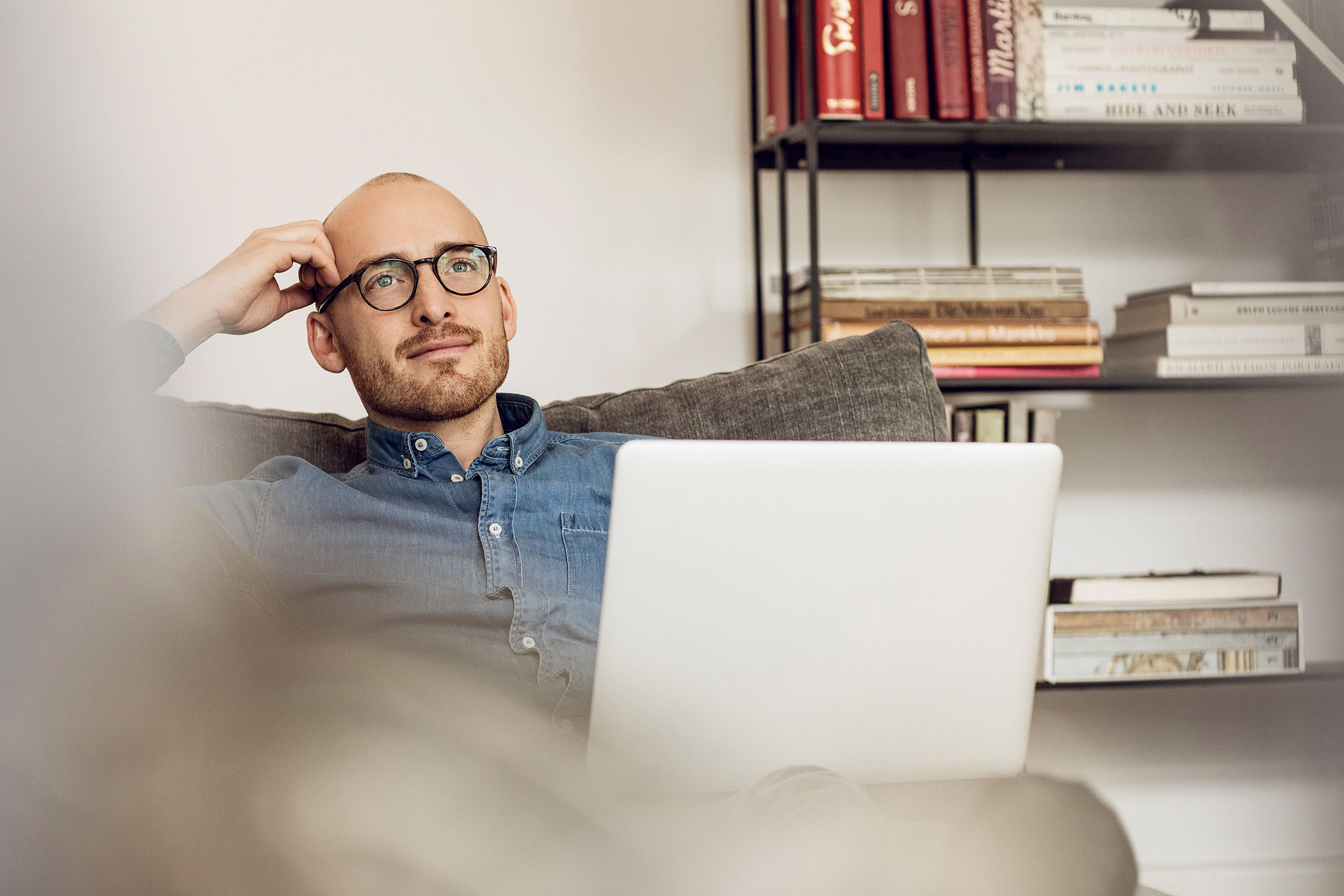 Mann sitzt auf der Couch und benutzt ein Laptop