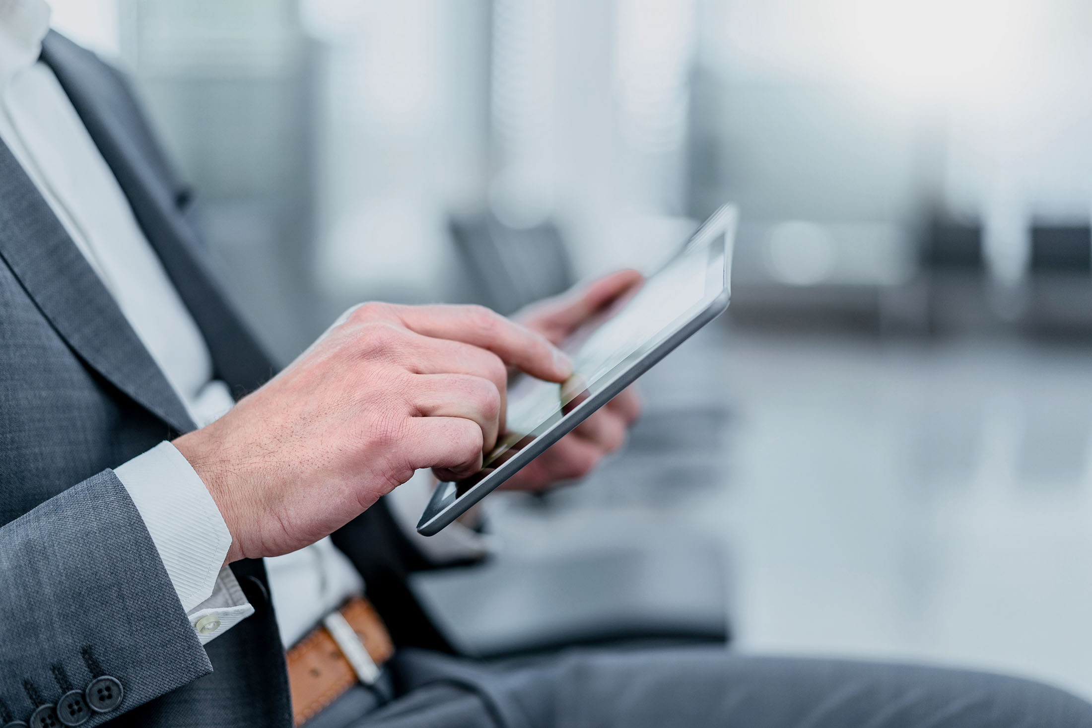 Geschäftsmann sitzt im Wartebereich und nutzt ein Tablet