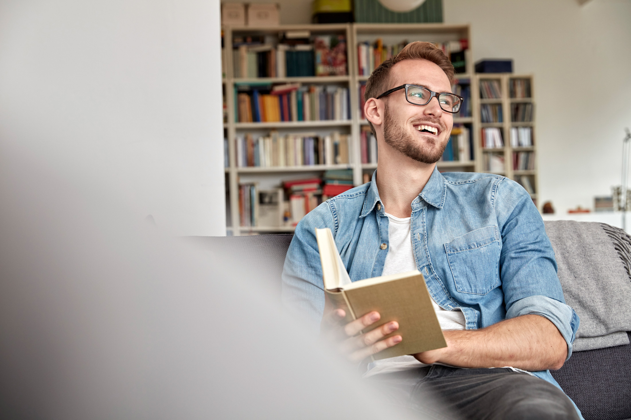 Lächelnder junger Mann liest ein Buch.