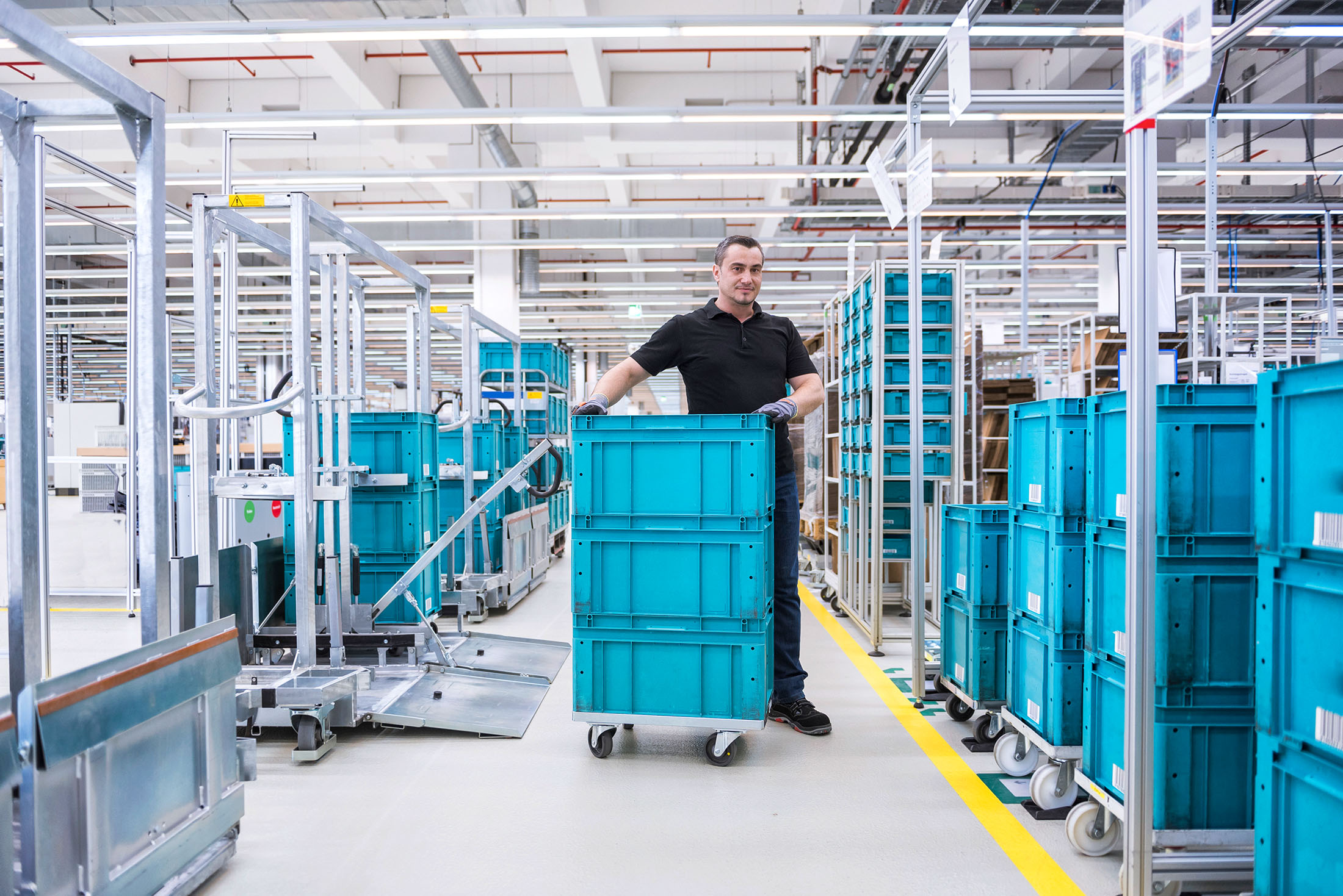 Mann steht hinter Boxen in einer Lagerhalle