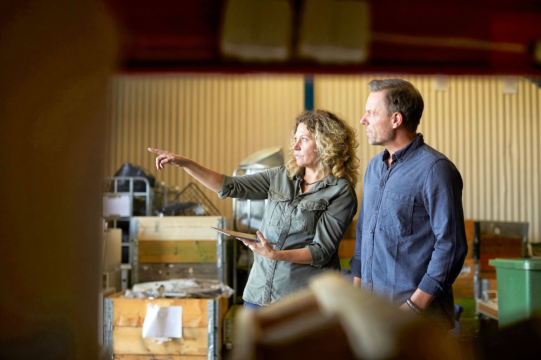 Zwei Kollegen stehen in der Produkthalle, besprechen sich und halten ein Tablet in der Hand