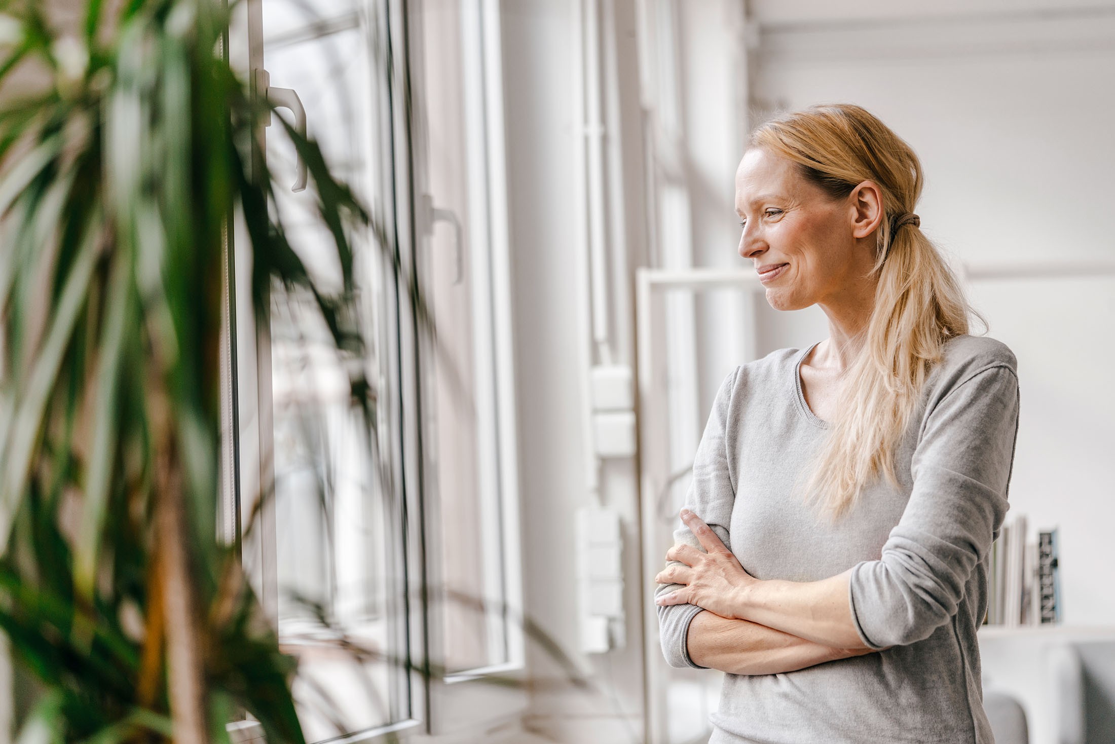 Lächelnde Frau steht vorm Fenster