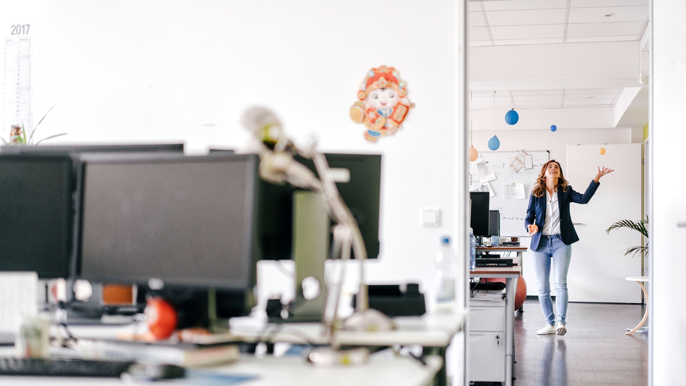 Glückliche Geschäftsfrau jongliert Bälle im Büro