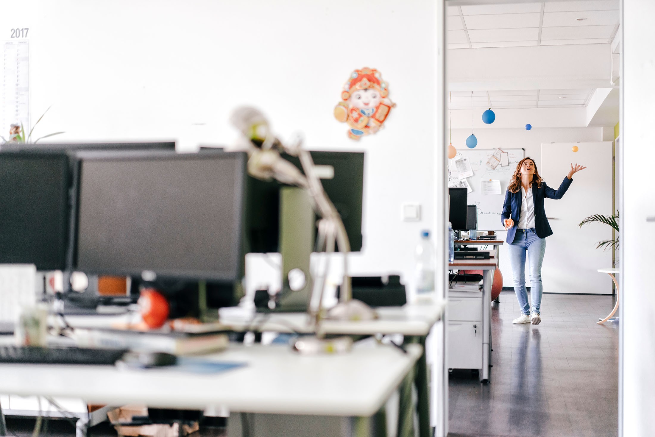 Glückliche Geschäftsfrau jongliert Bälle im Büro