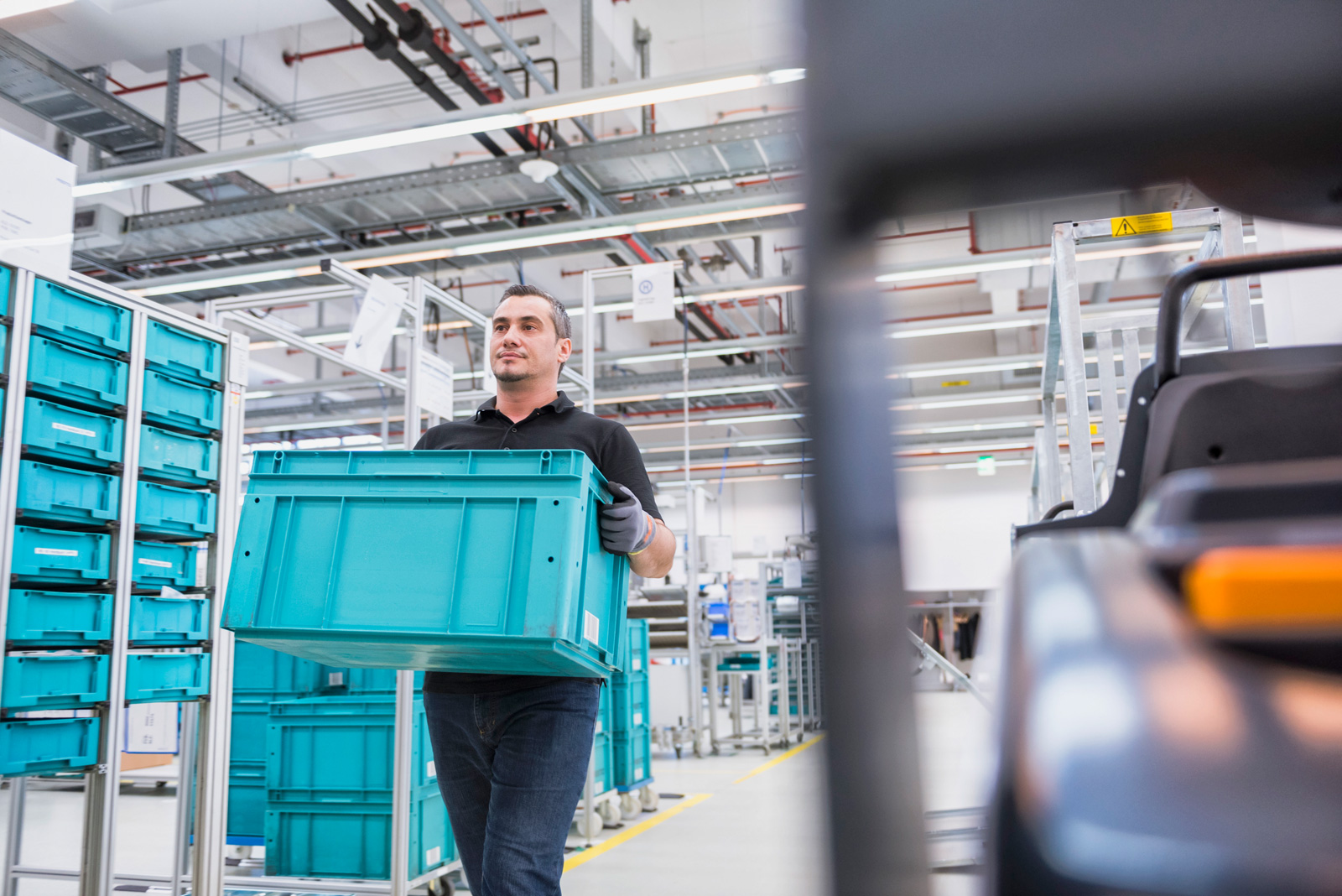 Arbeiter trägt Box durch Produktionshalle