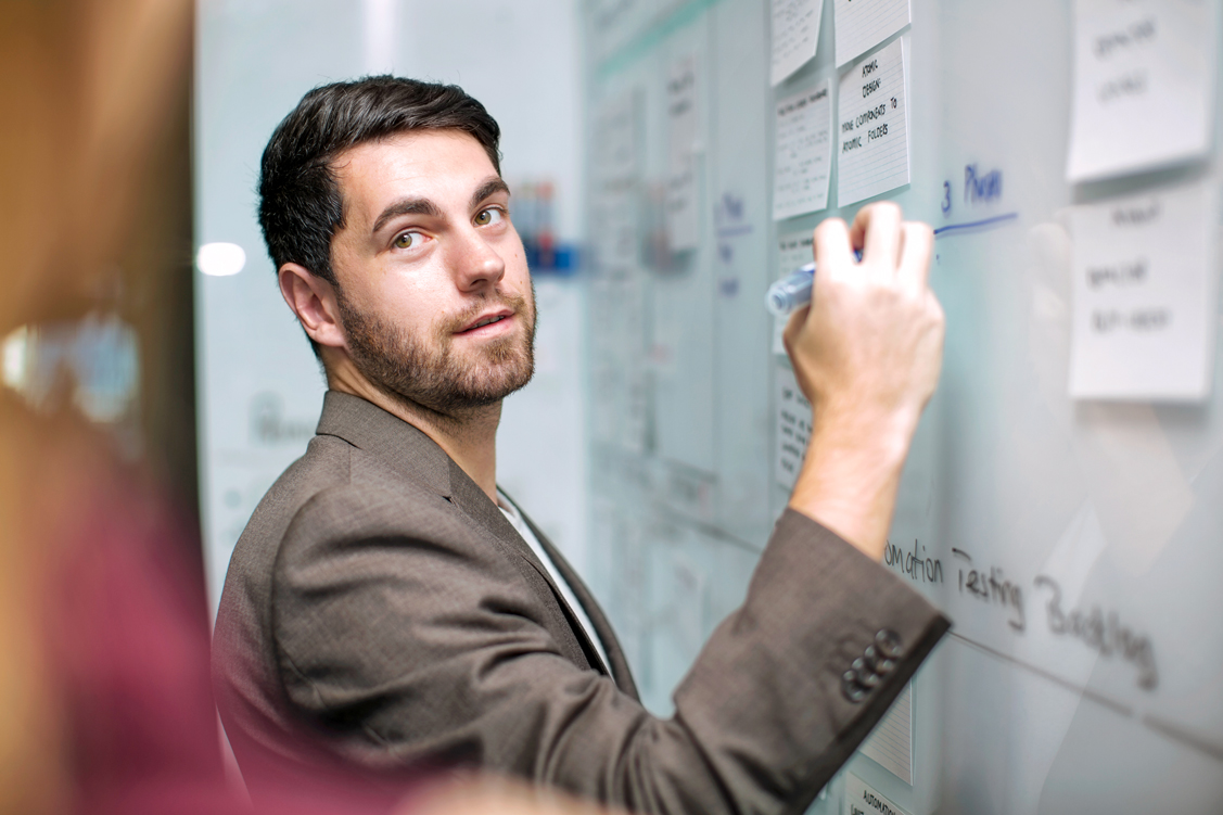 Mann schreibt Notizen auf ein Whiteboard